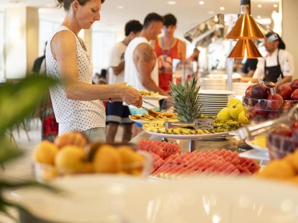 Buffet de fruits frais avec des personnes se servant.