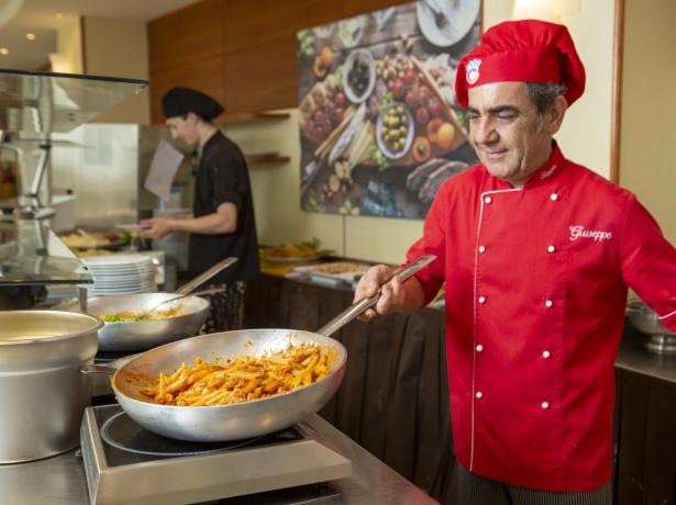 Chef cooking pasta in a professional kitchen.