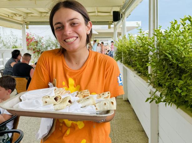 Smiling girl with food tray in an outdoor restaurant.