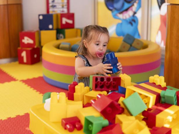 Child playing with colorful blocks in a play area.